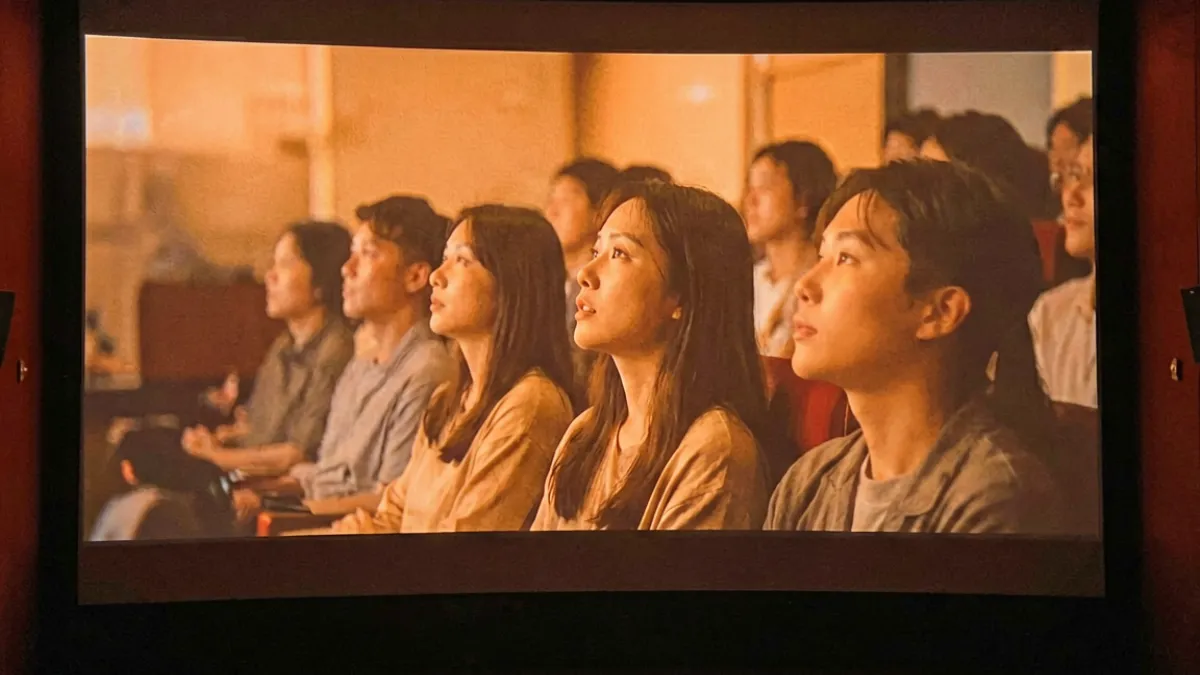 影院大屏幕播放蜜桃成熟时经典场景，座位上观众聚精会神，侧脸被荧幕光线映照